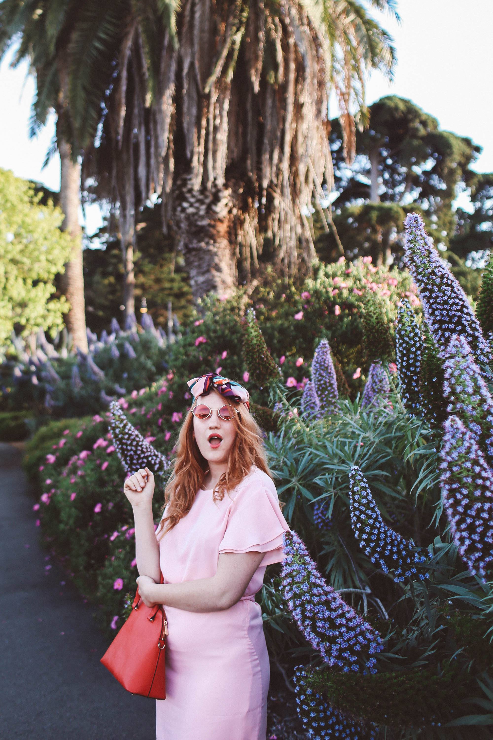 woman wearing headscarf, pink dress, pink sunglasses in flowers