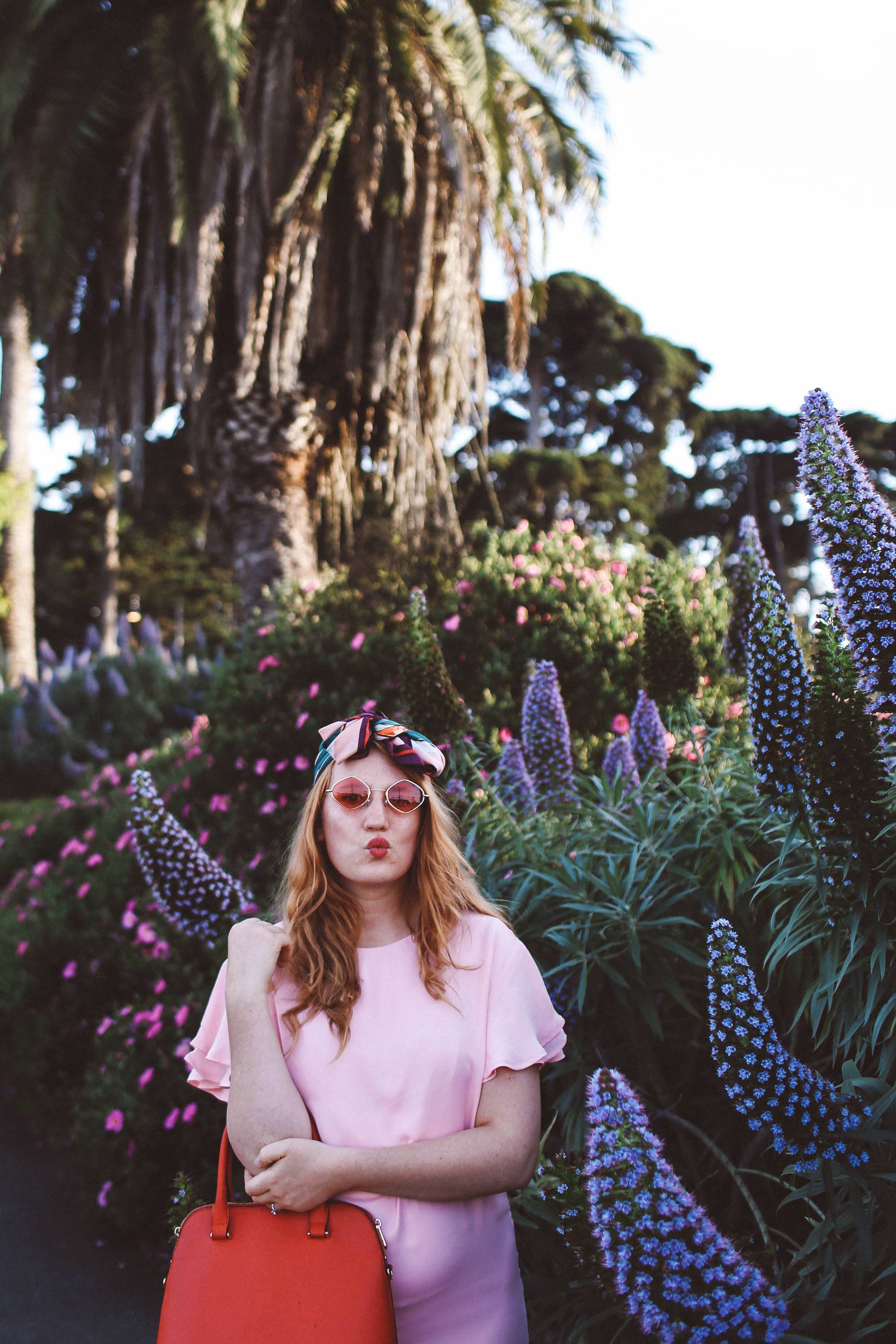 woman wearing headscarf, pink dress, pink sunglasses in flowers