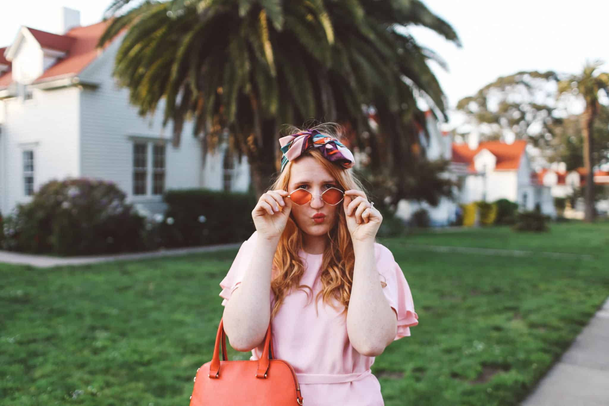 woman wearing headscarf, pink dress, pink sunglasses in flowers