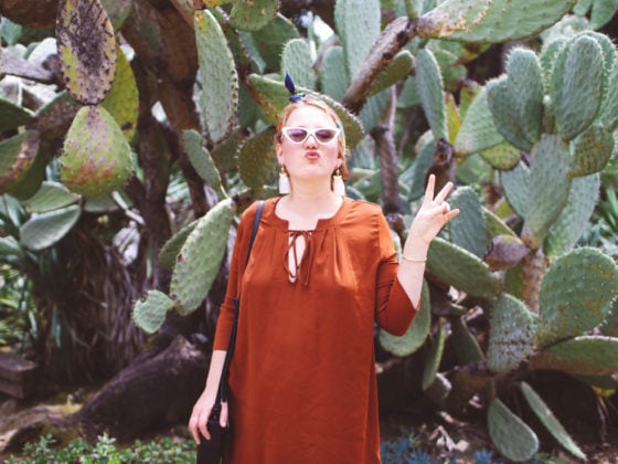 Woman in burnt orange dress in front of cacti