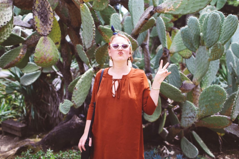 Woman in burnt orange dress in front of cacti
