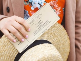 Woman holding Napa Valley Wine Train ticket and a straw hat