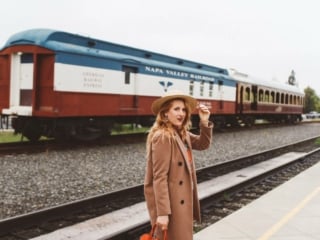 Woman in a tan coat and straw hat on the platform at Napa Vallley Wine Train