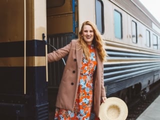 Woman in a red floral dress hanging off of the Napa Valley Wine Train