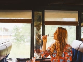 Woman in a red floral dress drinking wine on the Napa Valley Wine Train