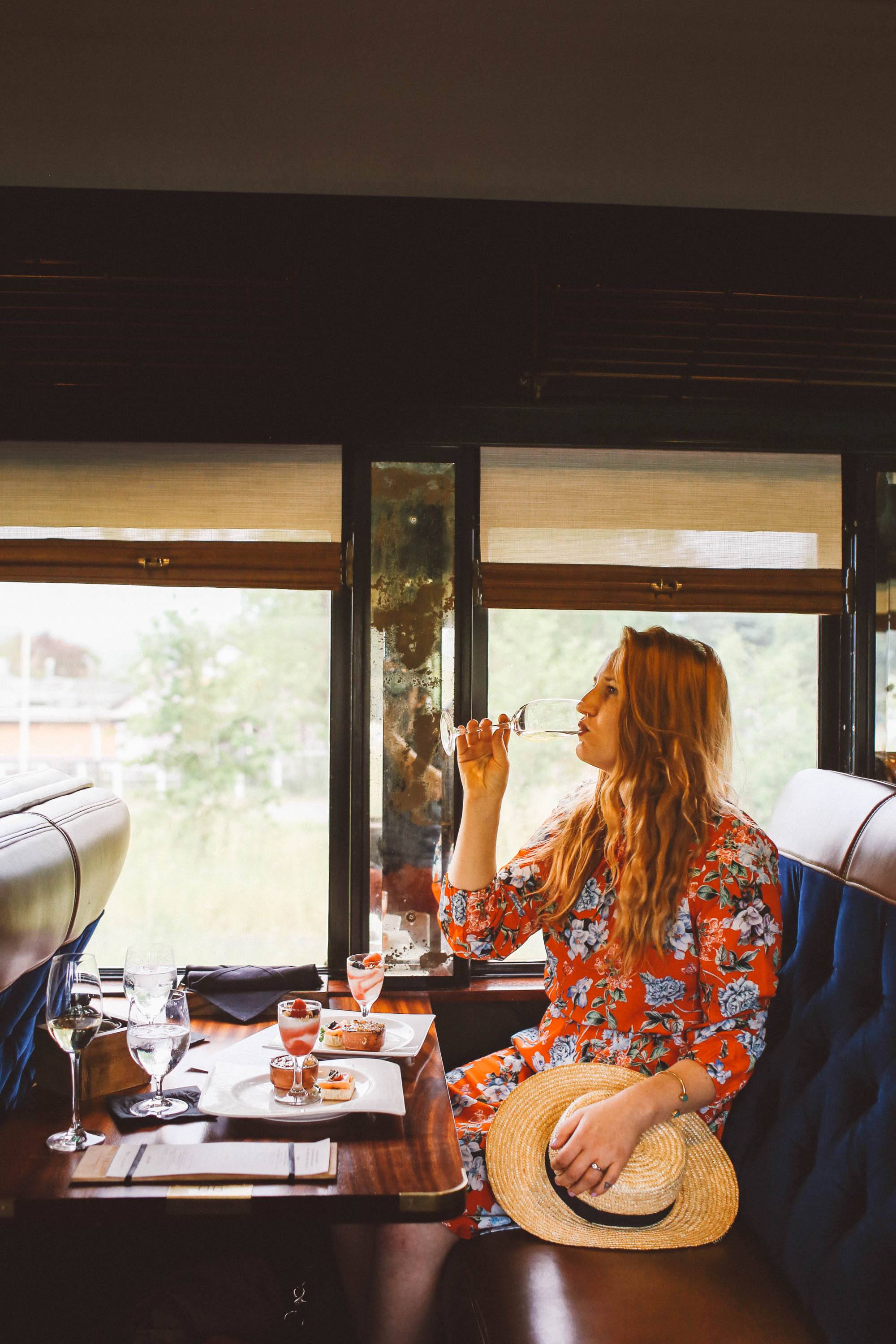 Woman in a red floral dress drinking wine on the Napa Valley Wine Train
