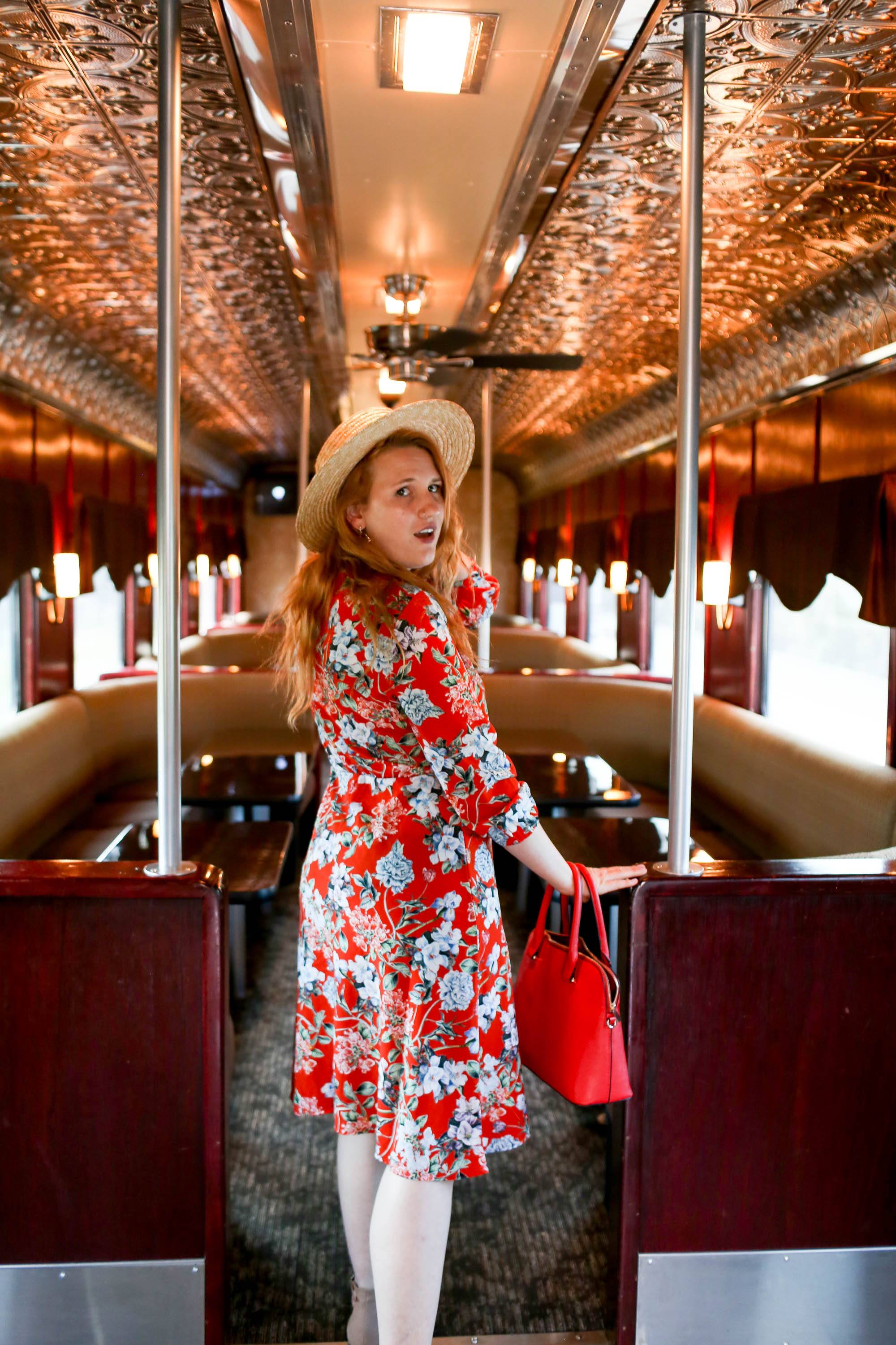 Woman in red floral dress standing in the aisle of the Napa Valley Wine Train