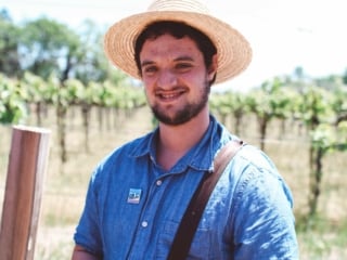 Man wearing straw hat in front of grapevines iat Whitehall Lane Vineyard