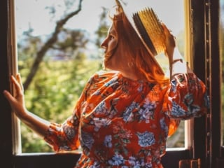 Woman in a red floral dress and a straw hat in front of a window on the Napa Valley Wine Train