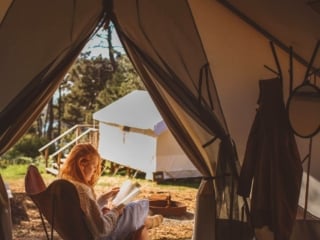 Woman reading in chair on tent porch