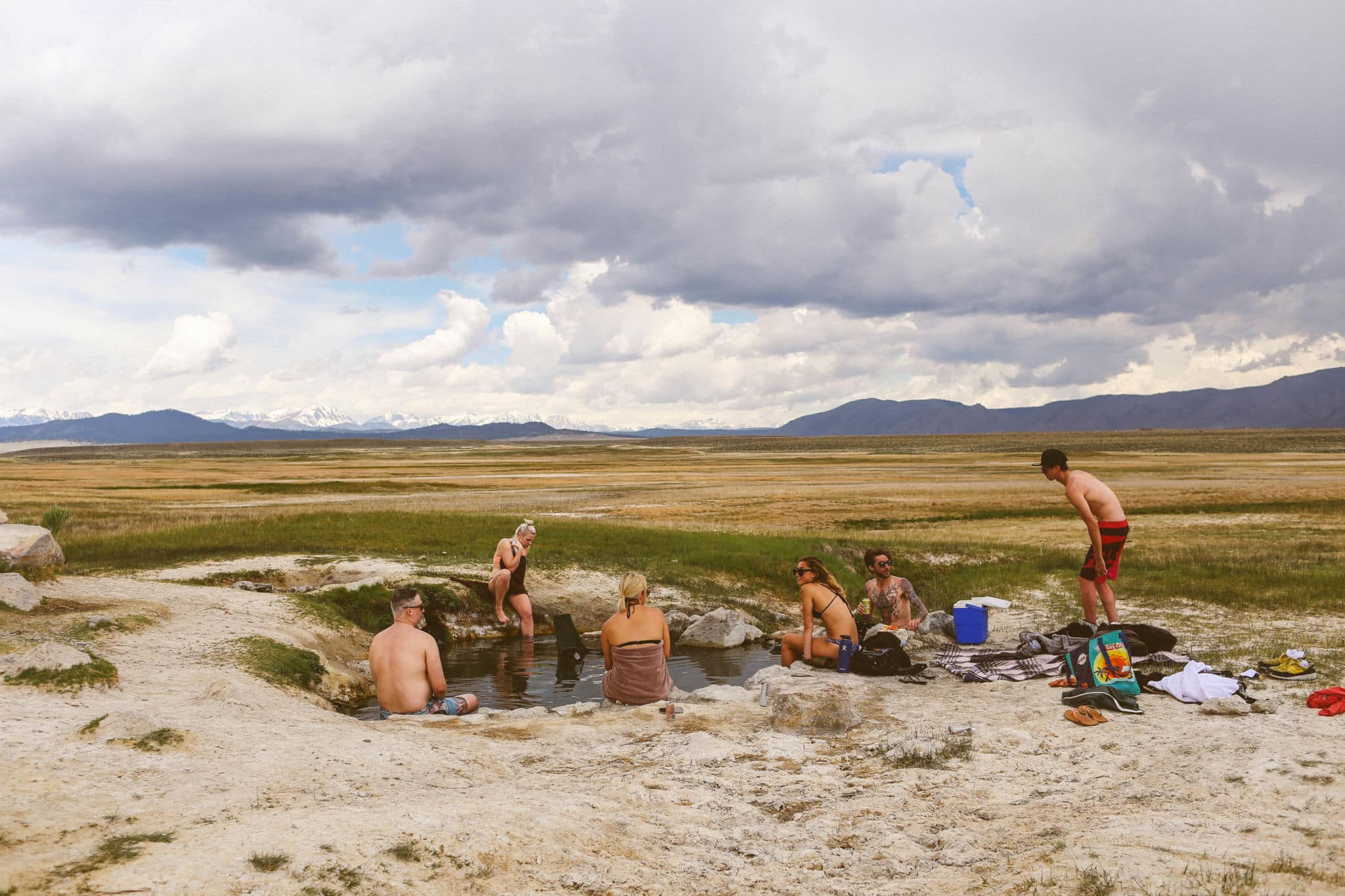 people sitting in a heart shaped hot spring in the mountains