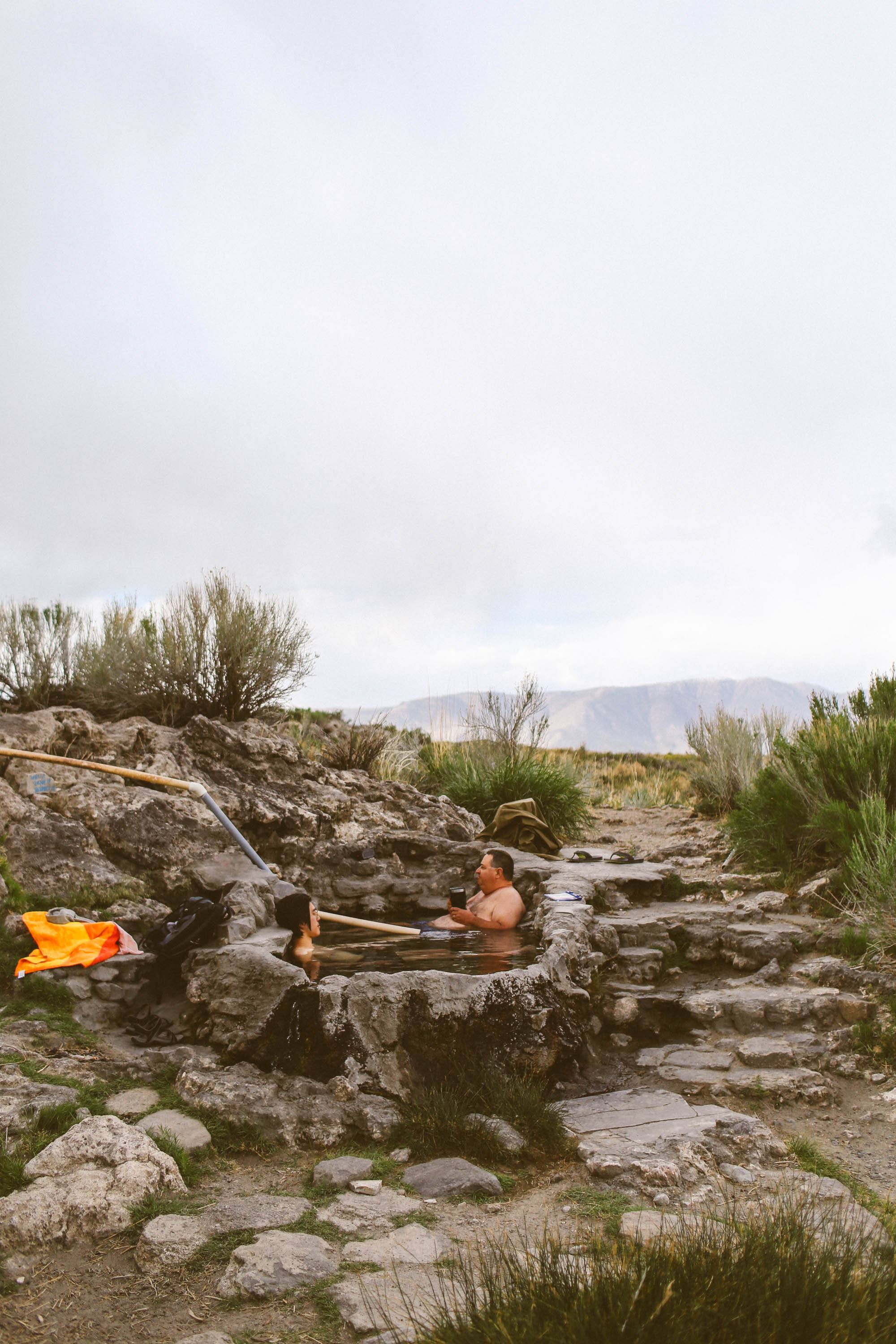 two people sitting in hot springs in the mountains