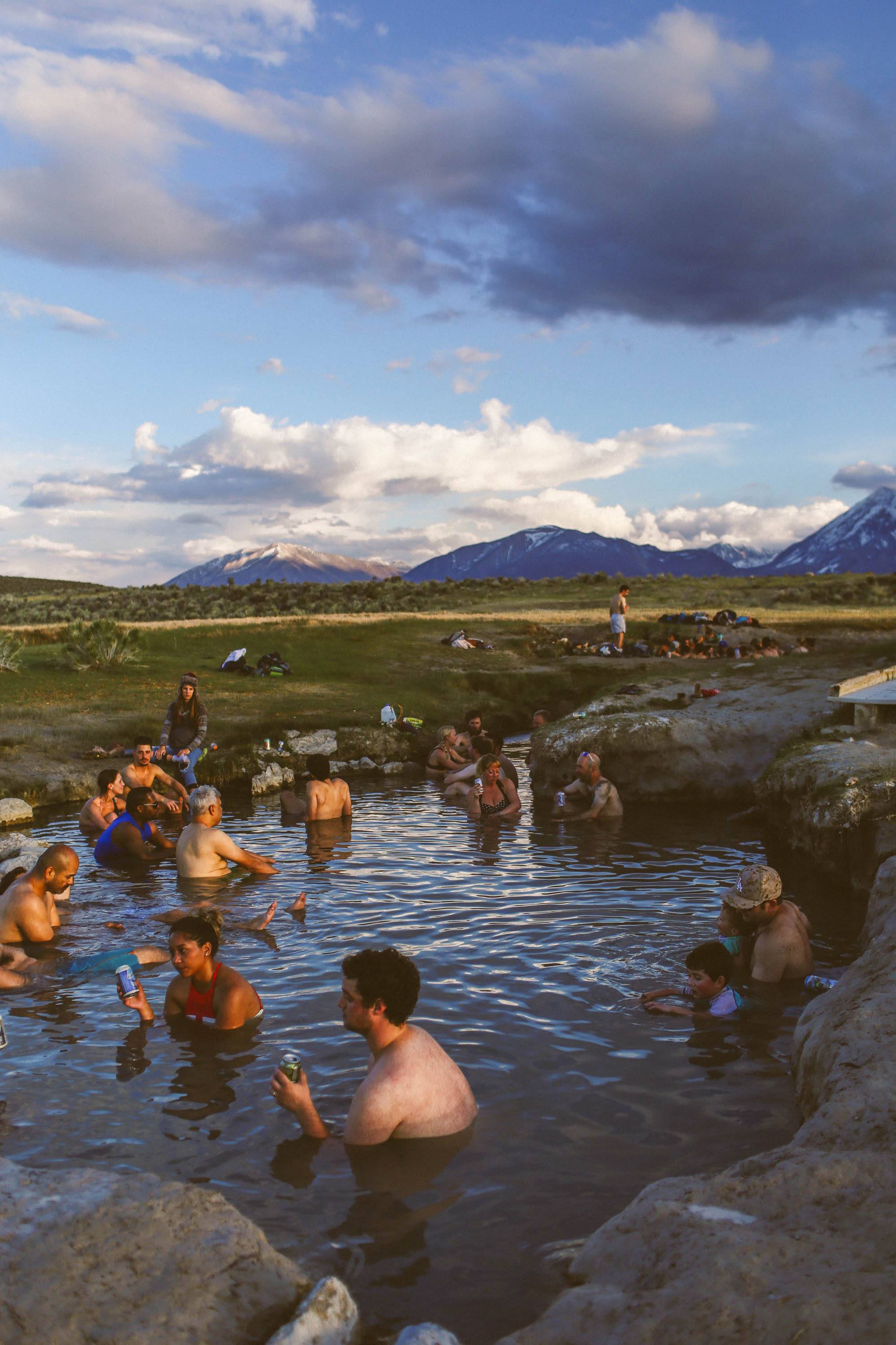 many people sitting in hot springs in the mountains