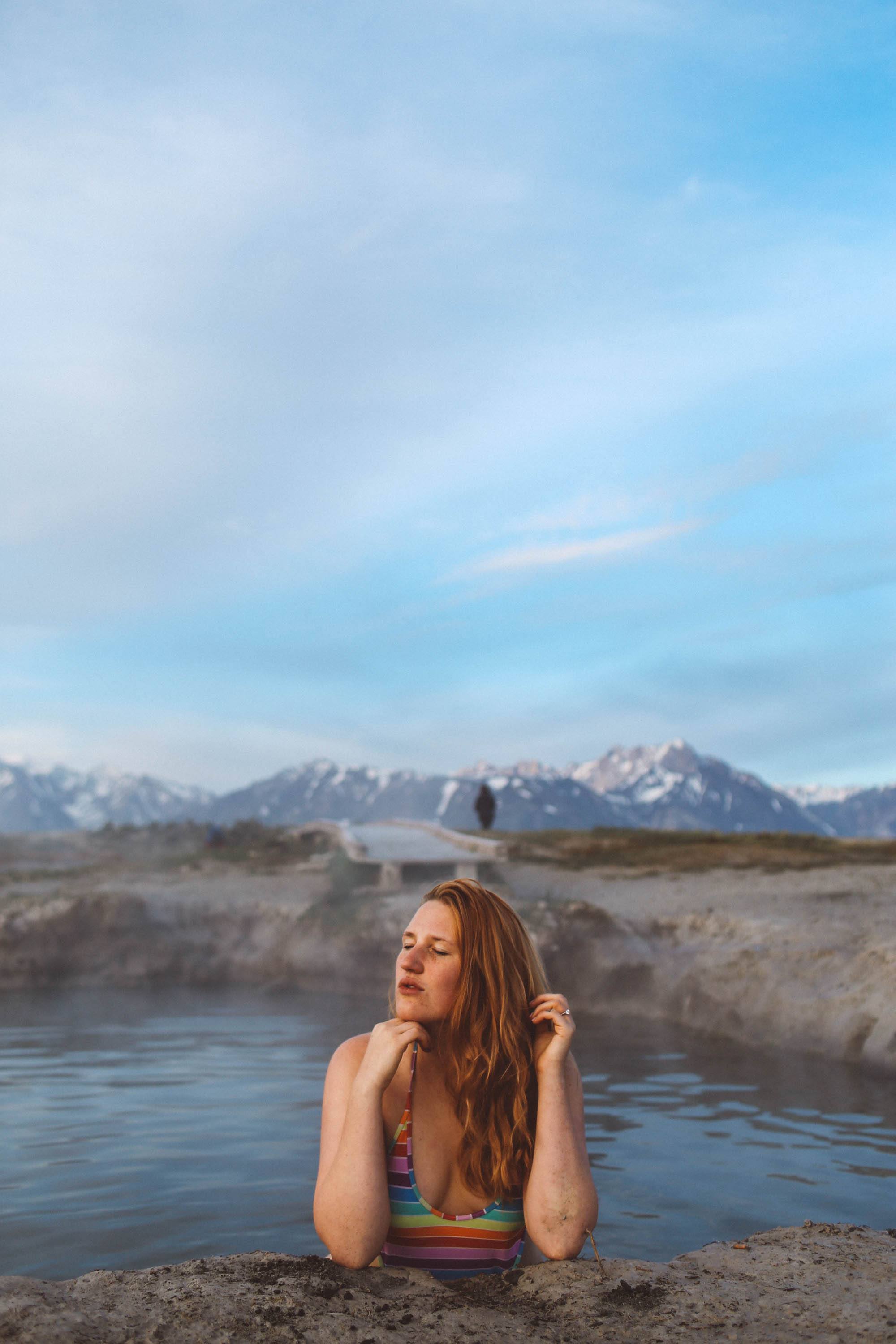 woman in a rainbow swimsuit in a hot spring in the mountains