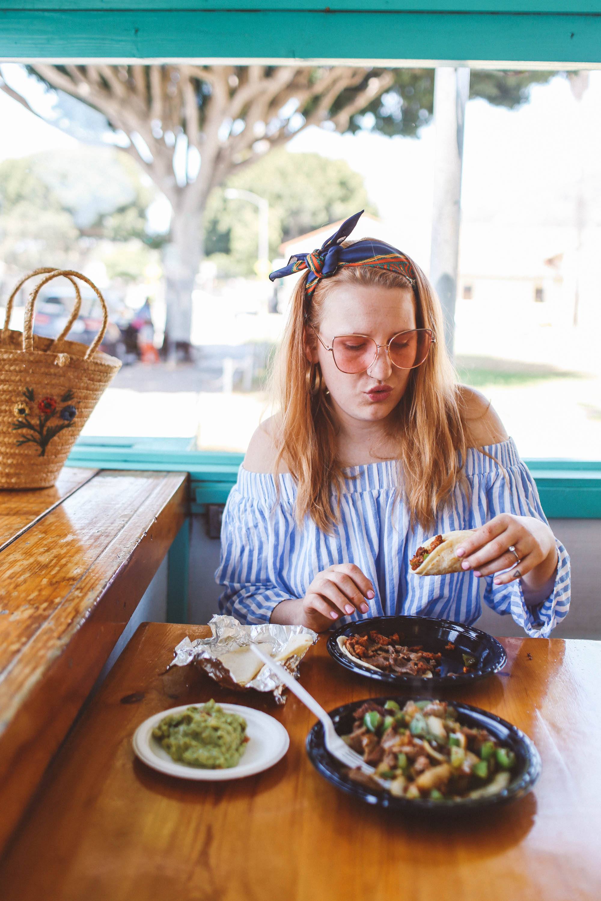 Woman in rose colored sunglasses eating tacos at La Super-ica Taqueria in Santa Barbara