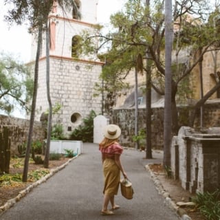 Woman wearing hat, red gingham top and a paper bag skirt at the Santa barbara mission