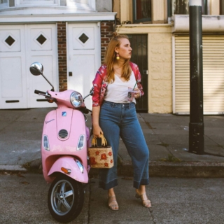 hand holding a Starbucks card next to a pink Vespa