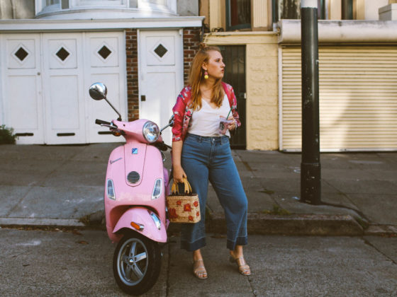 hand holding a Starbucks card next to a pink Vespa