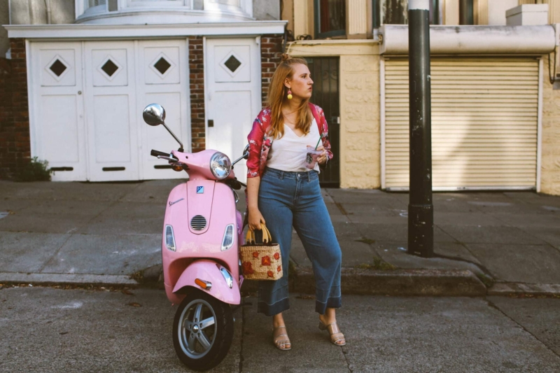 hand holding a Starbucks card next to a pink Vespa