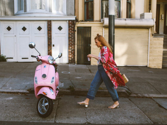 hand holding a Starbucks card next to a pink Vespa