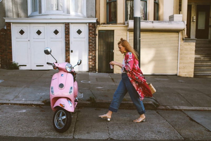 hand holding a Starbucks card next to a pink Vespa