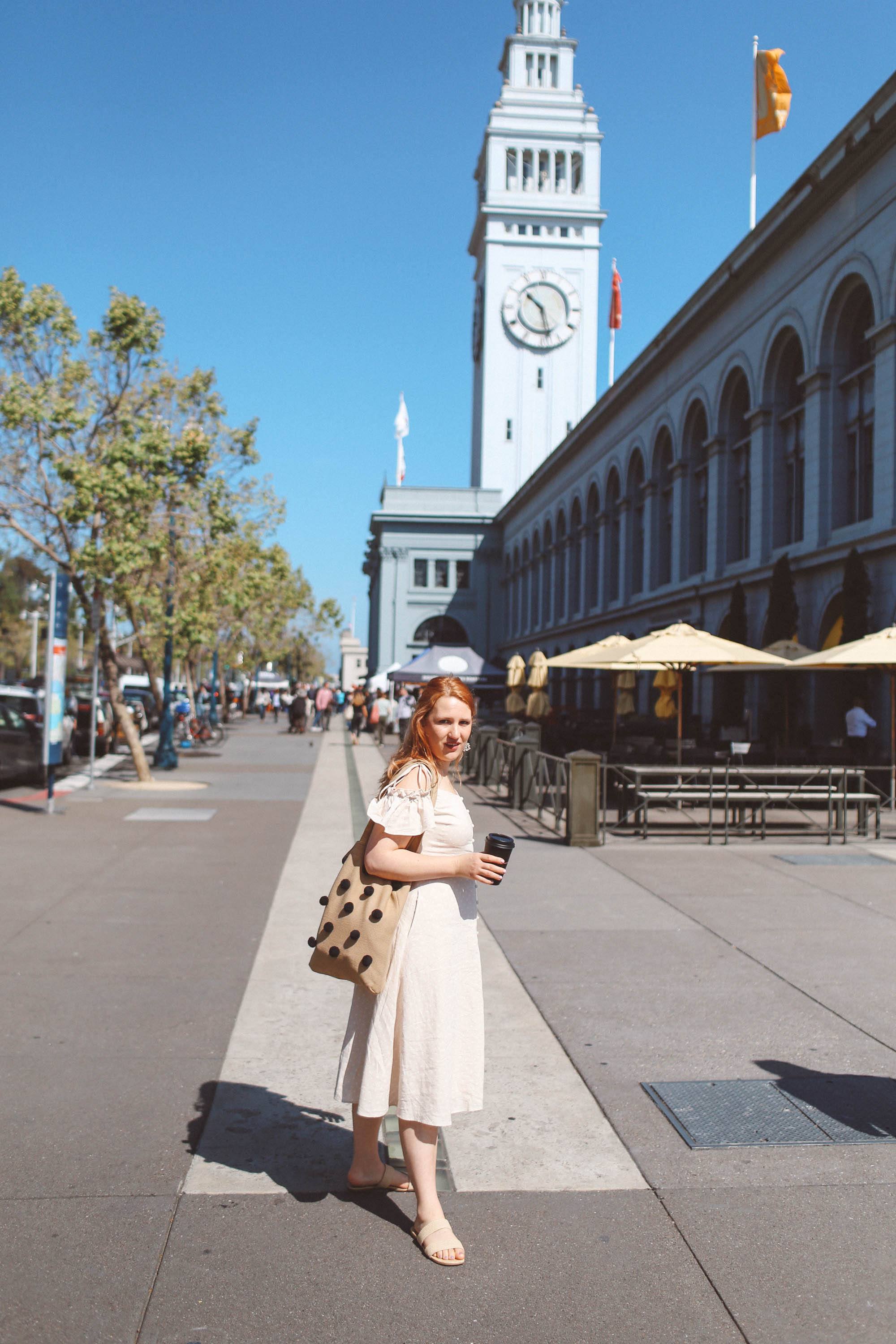 Woman wearing vintage dress holding coffee by ferry building