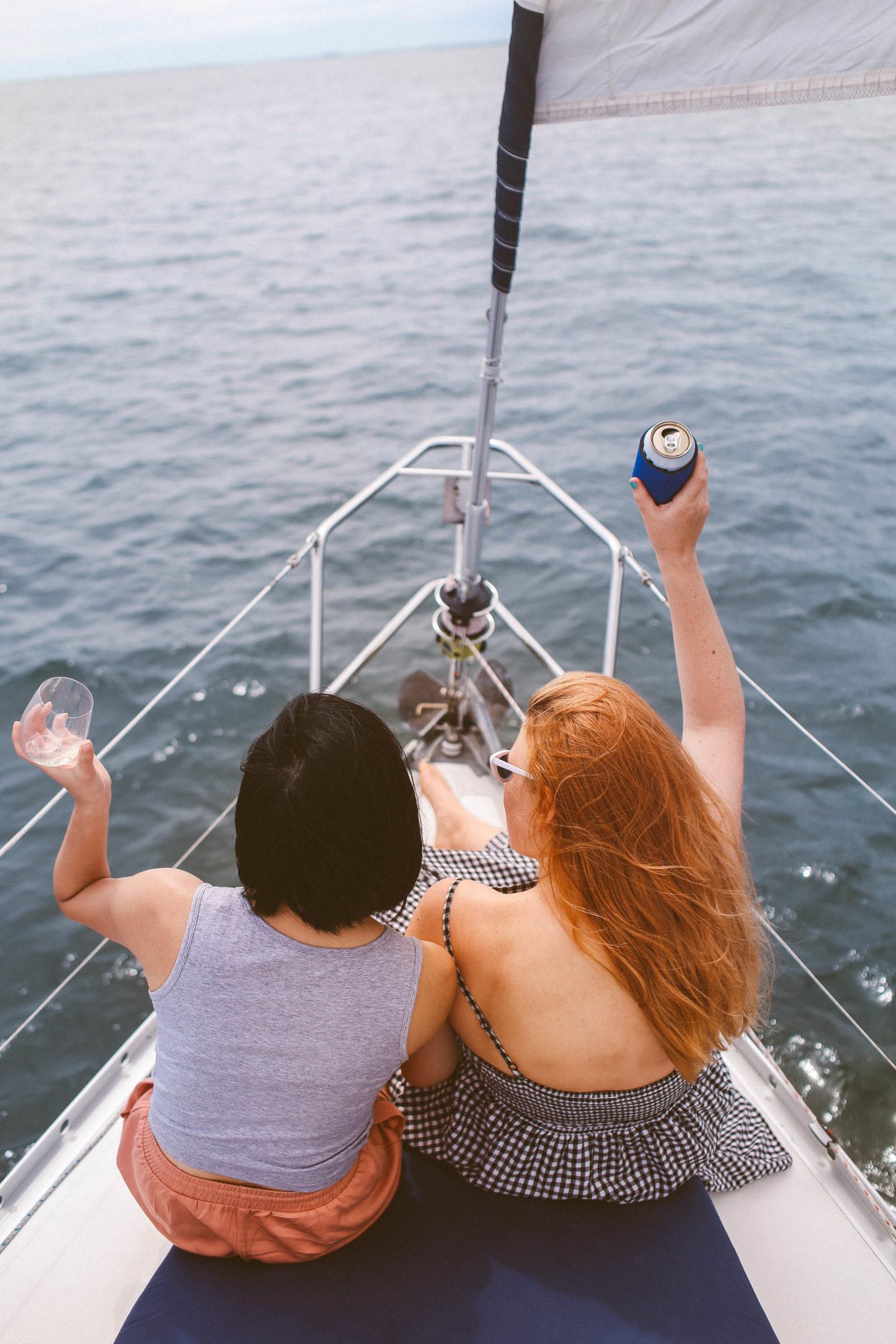 Two Woman holding drinks on the front of a sailboat on the Pensacola Bay