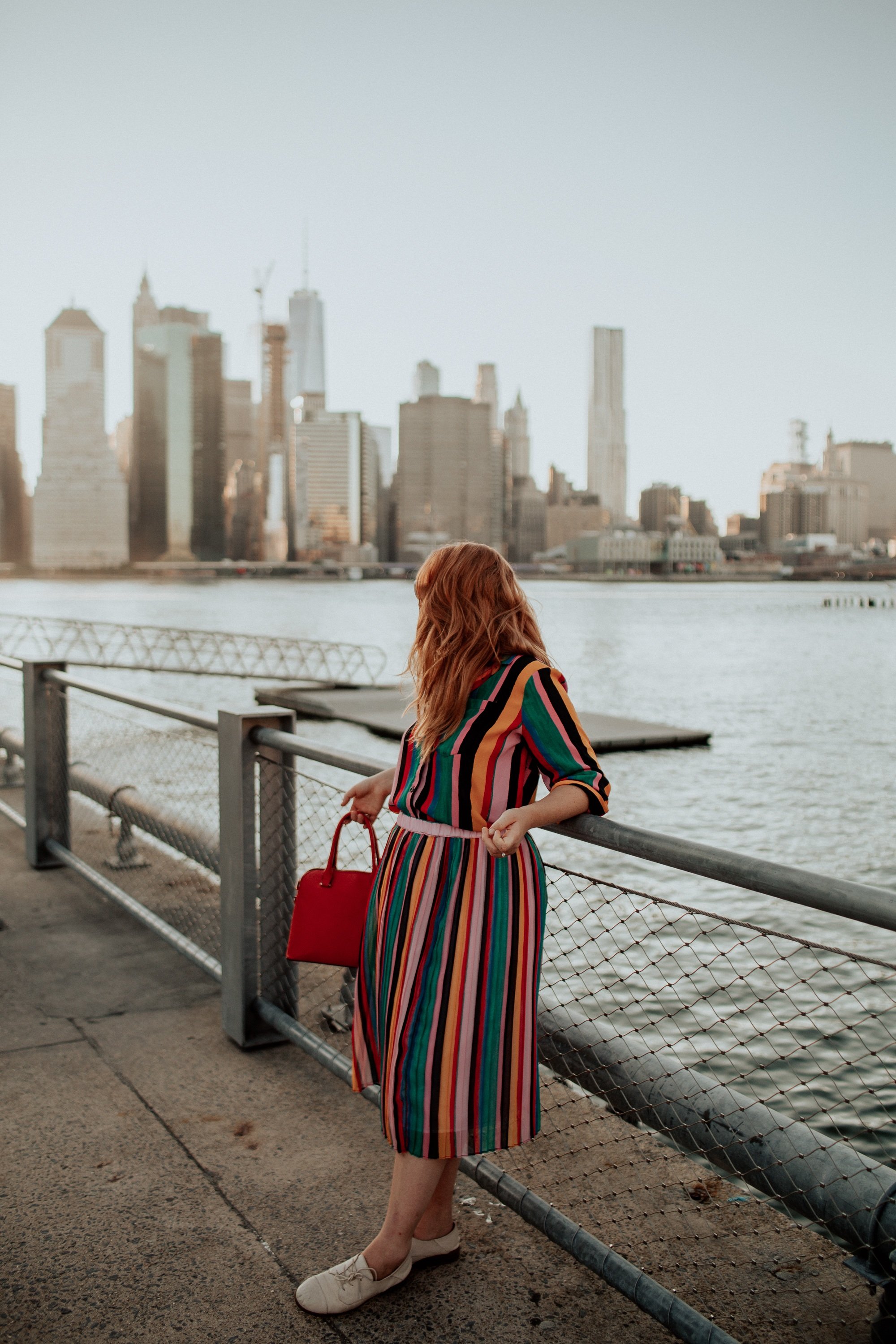 Woman in a Rainbow outfit looking at Manhattan from across the Hudson River.