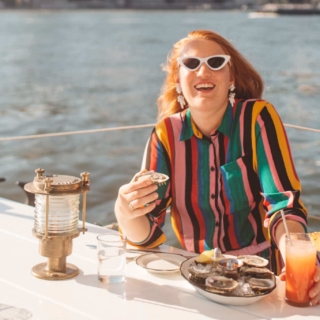 Woman in a rainbow outfit eating at a boat restaurant in Brooklyn