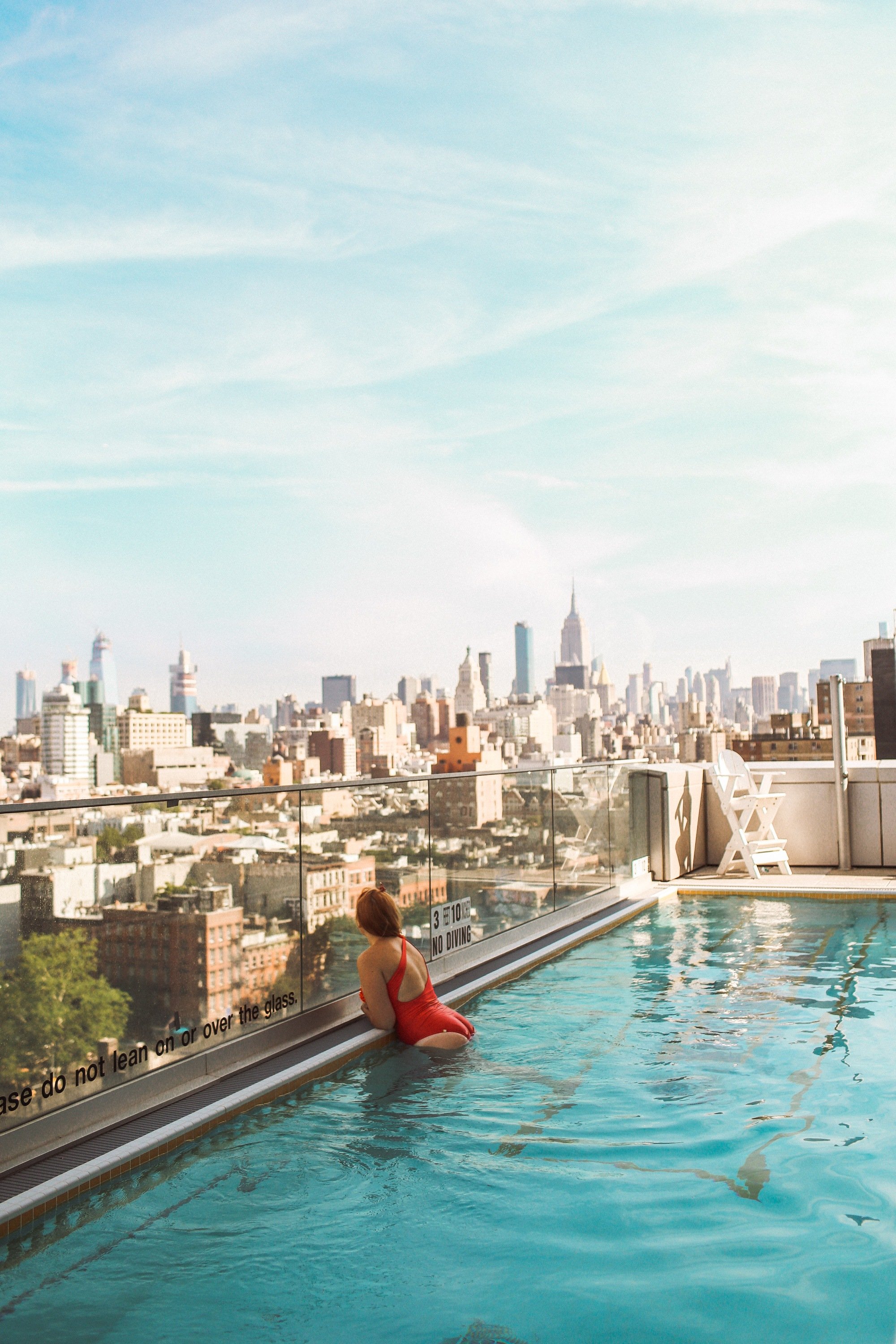 Woman looking out over Manhattan from a rooftop pool