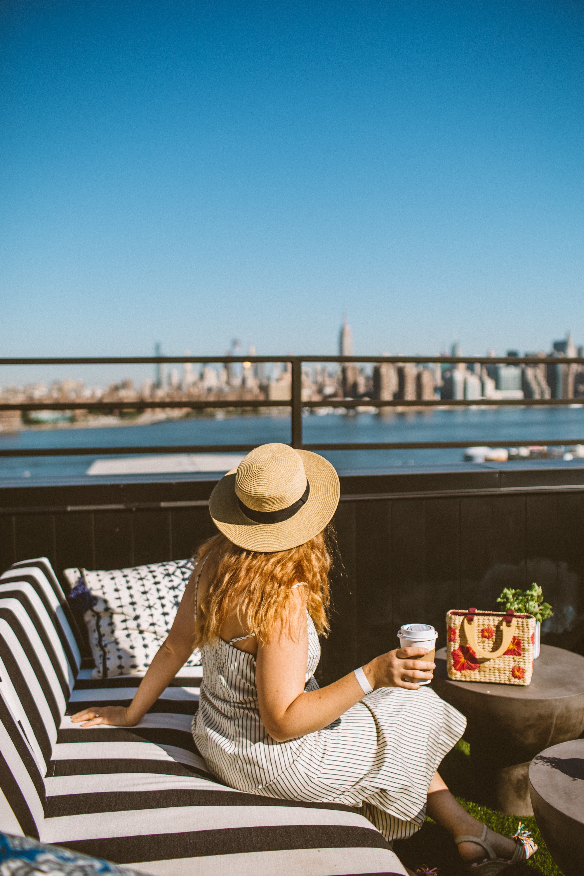 Woman in a striped dress sittiing on a couch on a rooftop in Brooklyn