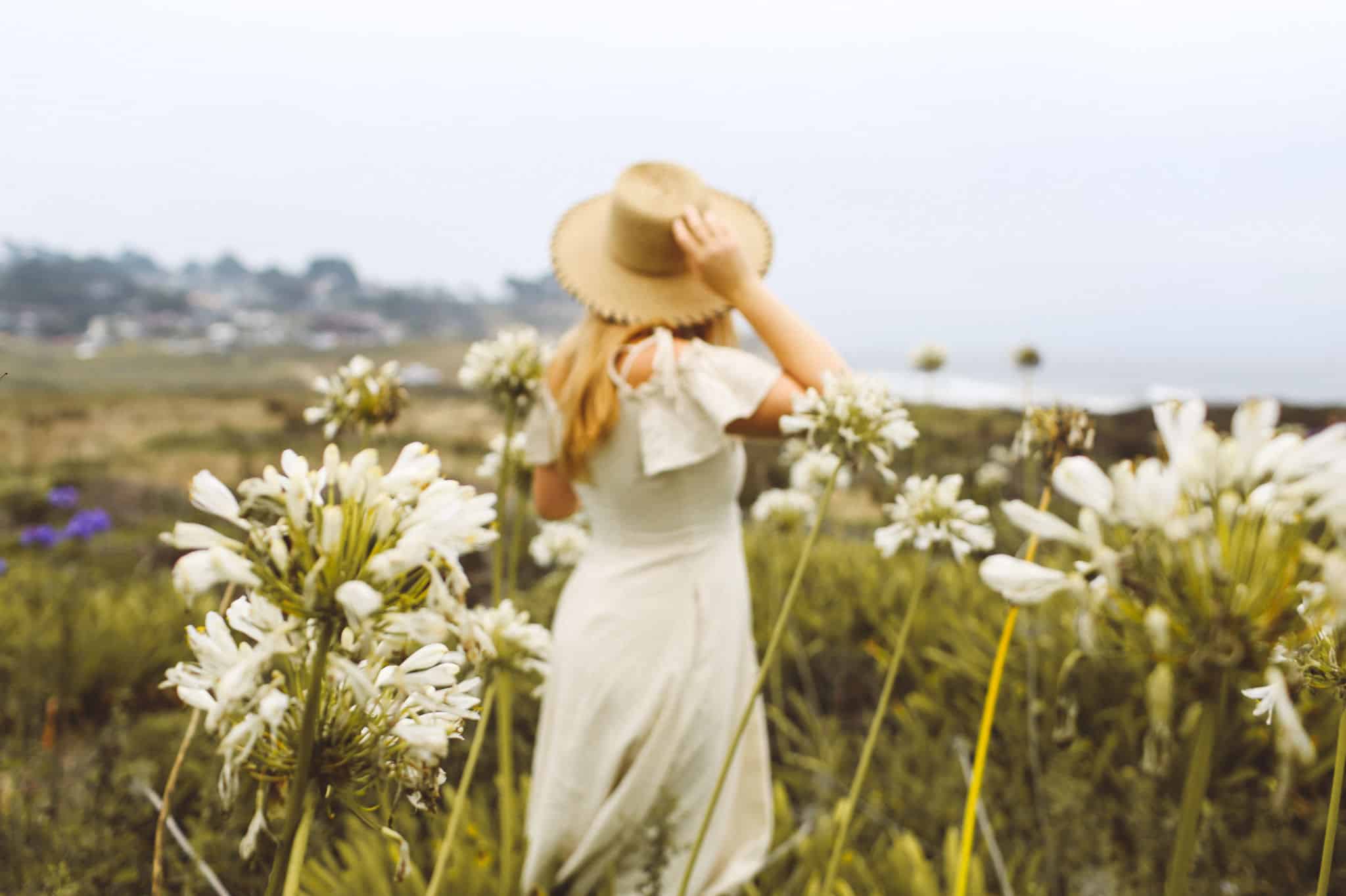 Woman in a dress and straw hat among the flowers