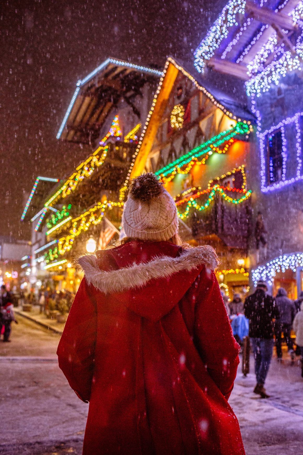 woman walking down string light lined street