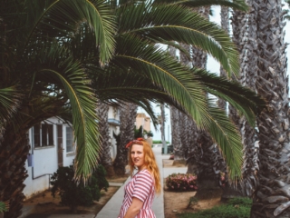 Wearing a red and white stripe dress amongst the palm trees in Oceanside, Ca