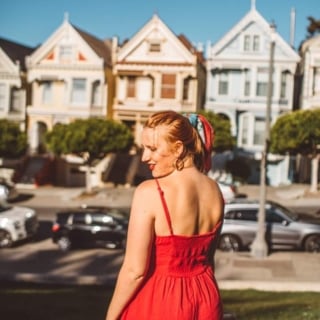 Kara of Whimsy Soul standing in front of the Painted Ladies in San Francisco wearing a red dress