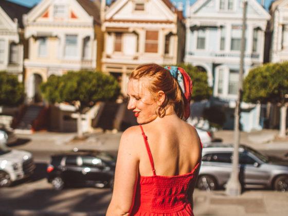 Kara of Whimsy Soul standing in front of the Painted Ladies in San Francisco wearing a red dress