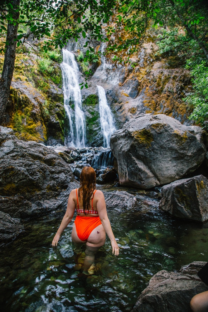 Kara of Whimsy Soul hikes to Feary Falls in Mount Shasta, a stunning small waterfall in Northern California. She is wearing an orange swimsuit