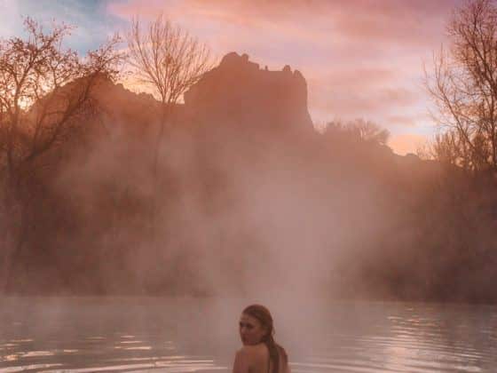 Kara of Whimsy Soul swimming in pool at sunrise next to Red Rocks at a Sedona Airbnb in Arizona