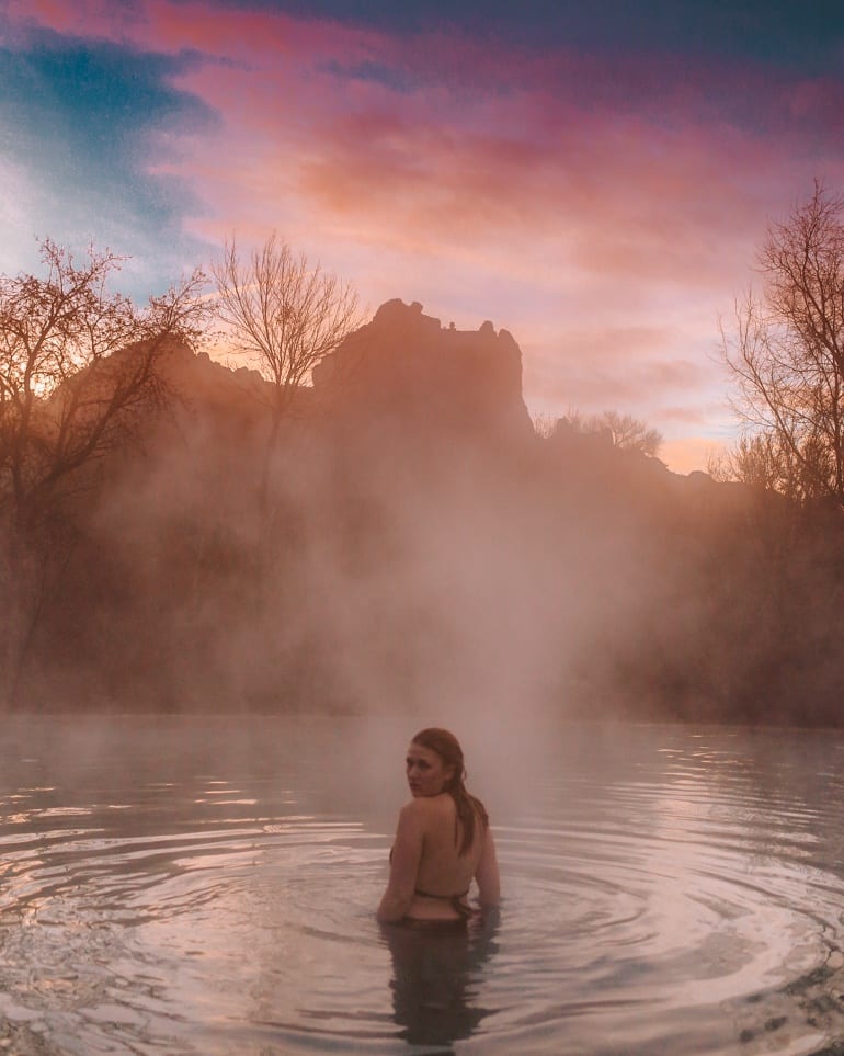 Kara of Whimsy Soul swimming in pool at sunrise next to Red Rocks at a Sedona Airbnb in Arizona