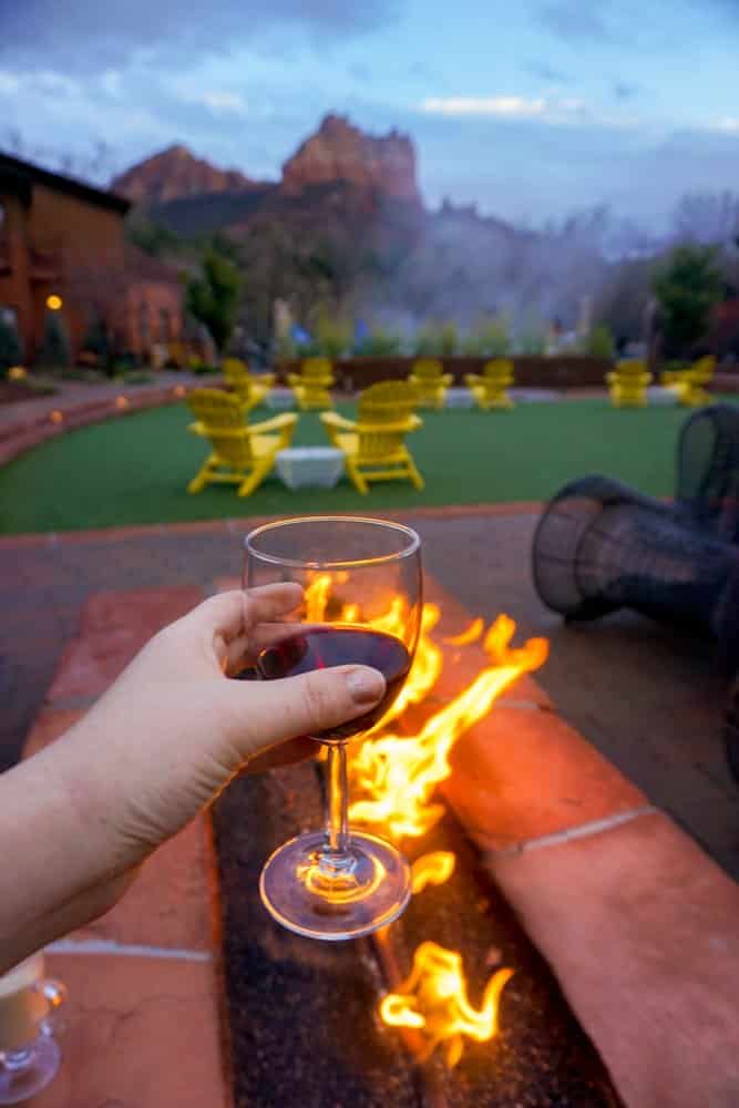Kara of Whimsy Soul enjoys a glass of wine in Sedona Arizona in her Airbnb next to a fire and Red Rocks