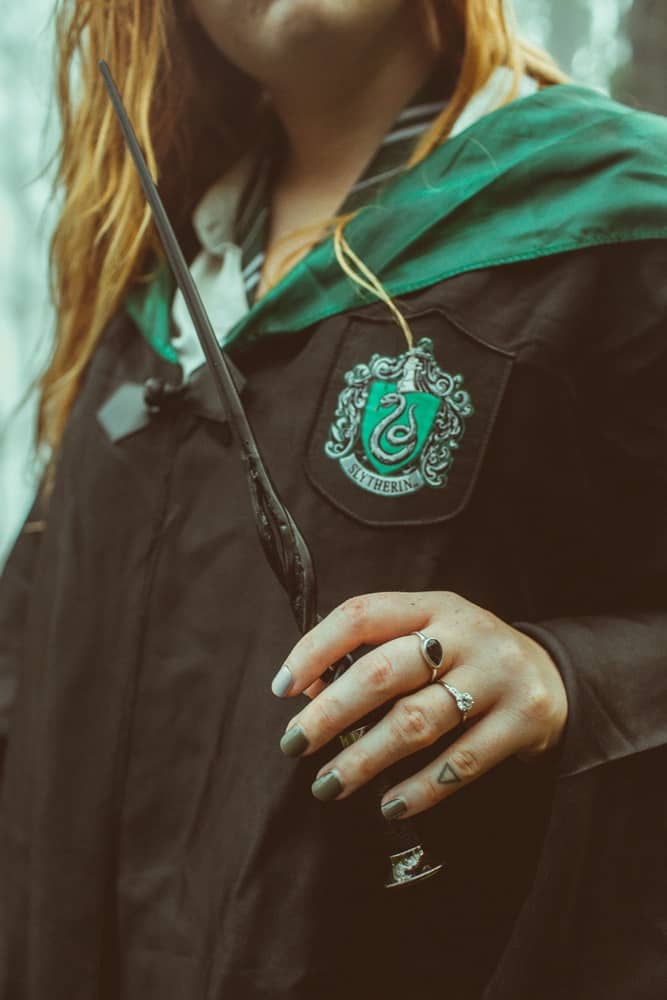 Kara holding her wand donning her Slytherin robes
