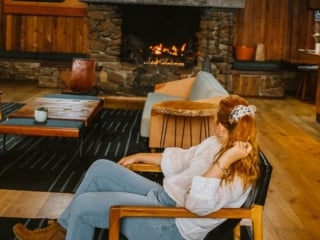 California travel blogger Kara Harms sits in the lobby of Timber Cove Resort wearing a white shirt and jeans